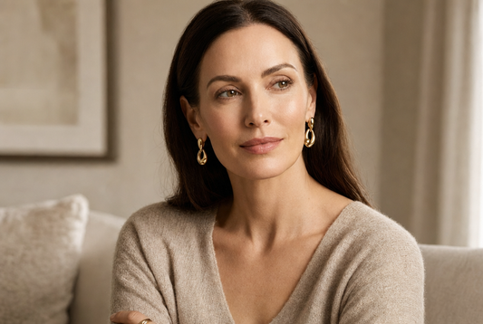 Woman in her 50s with rested, bright eyes at a window in soft daylight