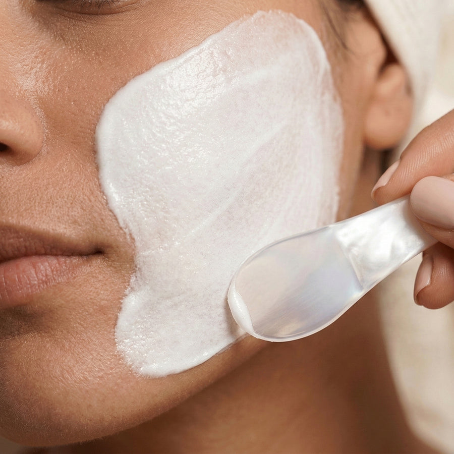 Person applying a white cream to their face with a spoon